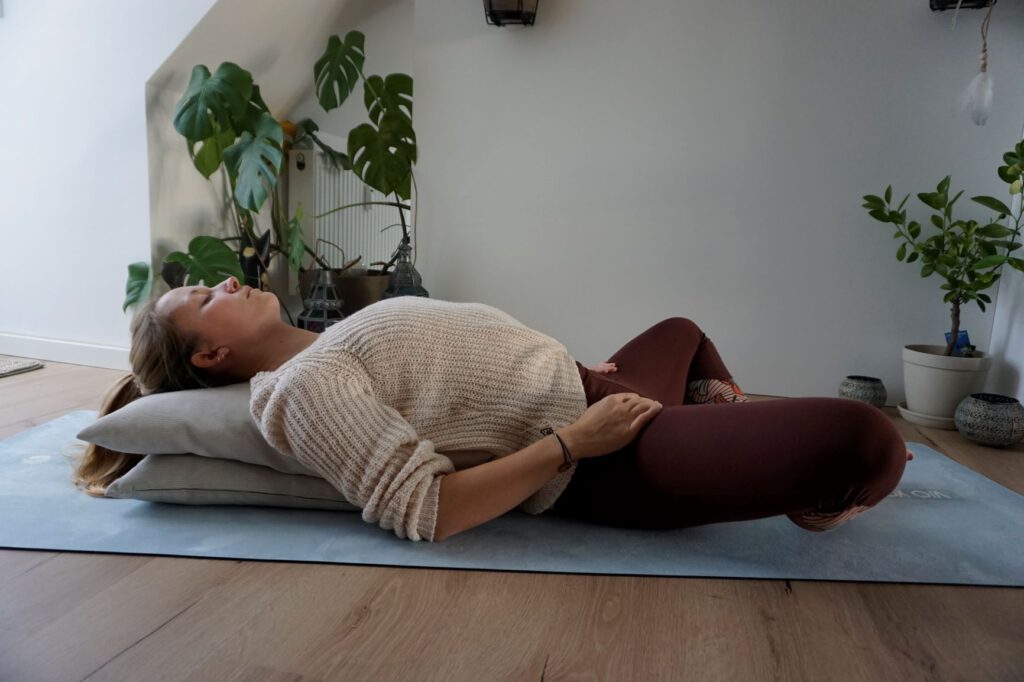 Jenny liegt unterstützt mit Decken in Rückenlage.