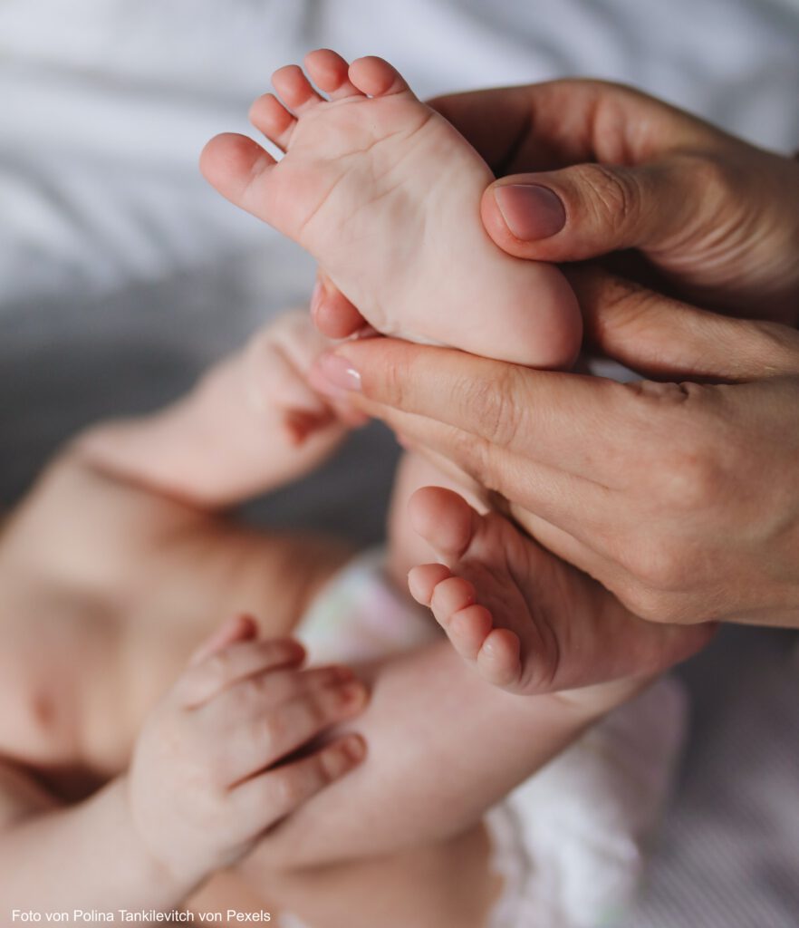 Baby liegt auf dem Rücken und wird massiert