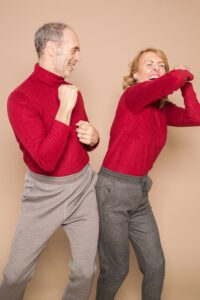 ein tanzendes älteres Paar mit roten Pollovern