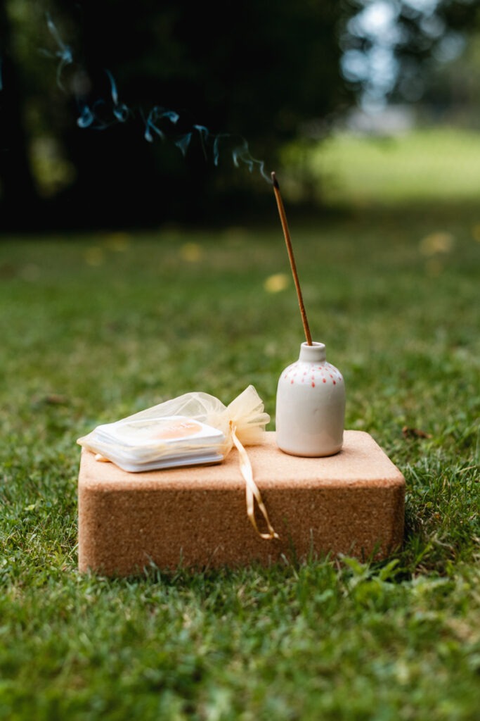 Yogablock aus Kork und darauf eine kleine Vase mit Räucherstäbchen und Achtsamkeitskarten.